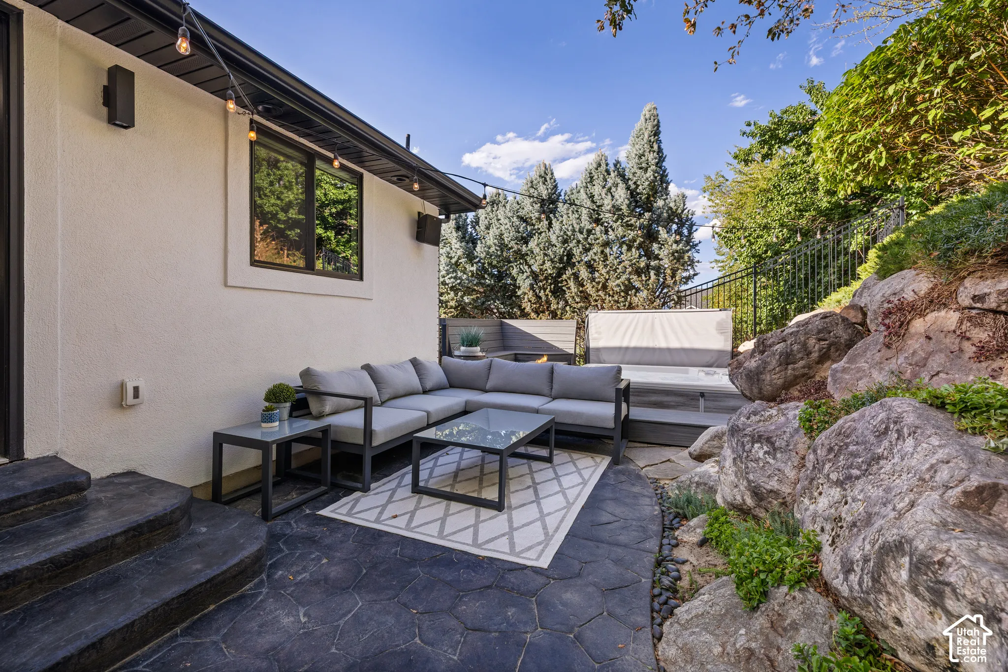 Outdoor patio featuring stamped concrete, multi-level decking, a built-in hot tub, and integrated rock landscaping