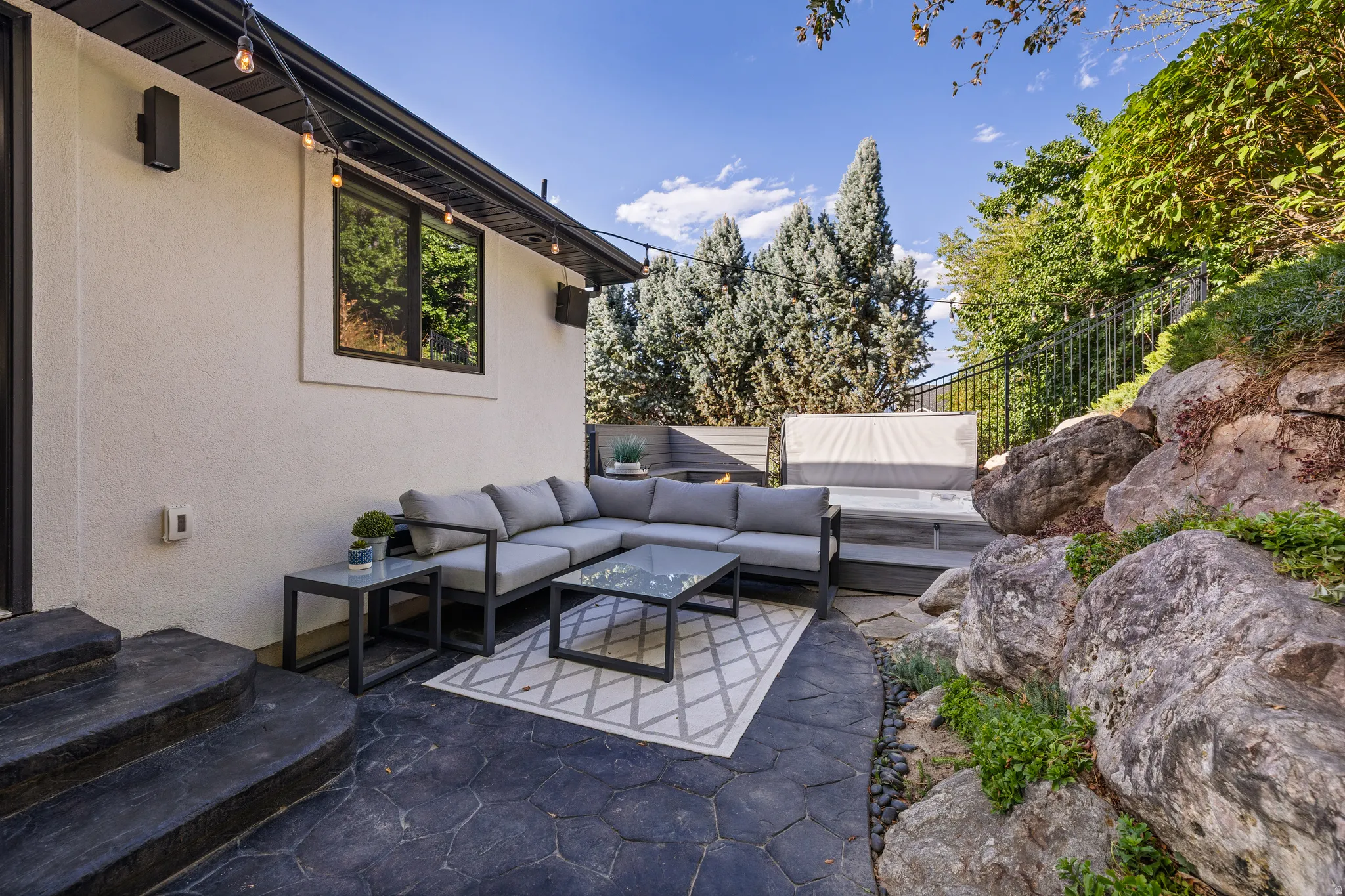 Outdoor patio featuring stamped concrete, multi-level decking, a built-in hot tub, and integrated rock landscaping