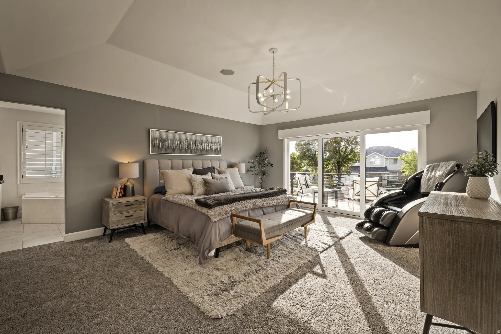 Tray ceiling with recessed lighting, modern chandelier, wall-to-wall carpeting, sliding glass door to exterior, and an en-suite bathroom with a built-in tub