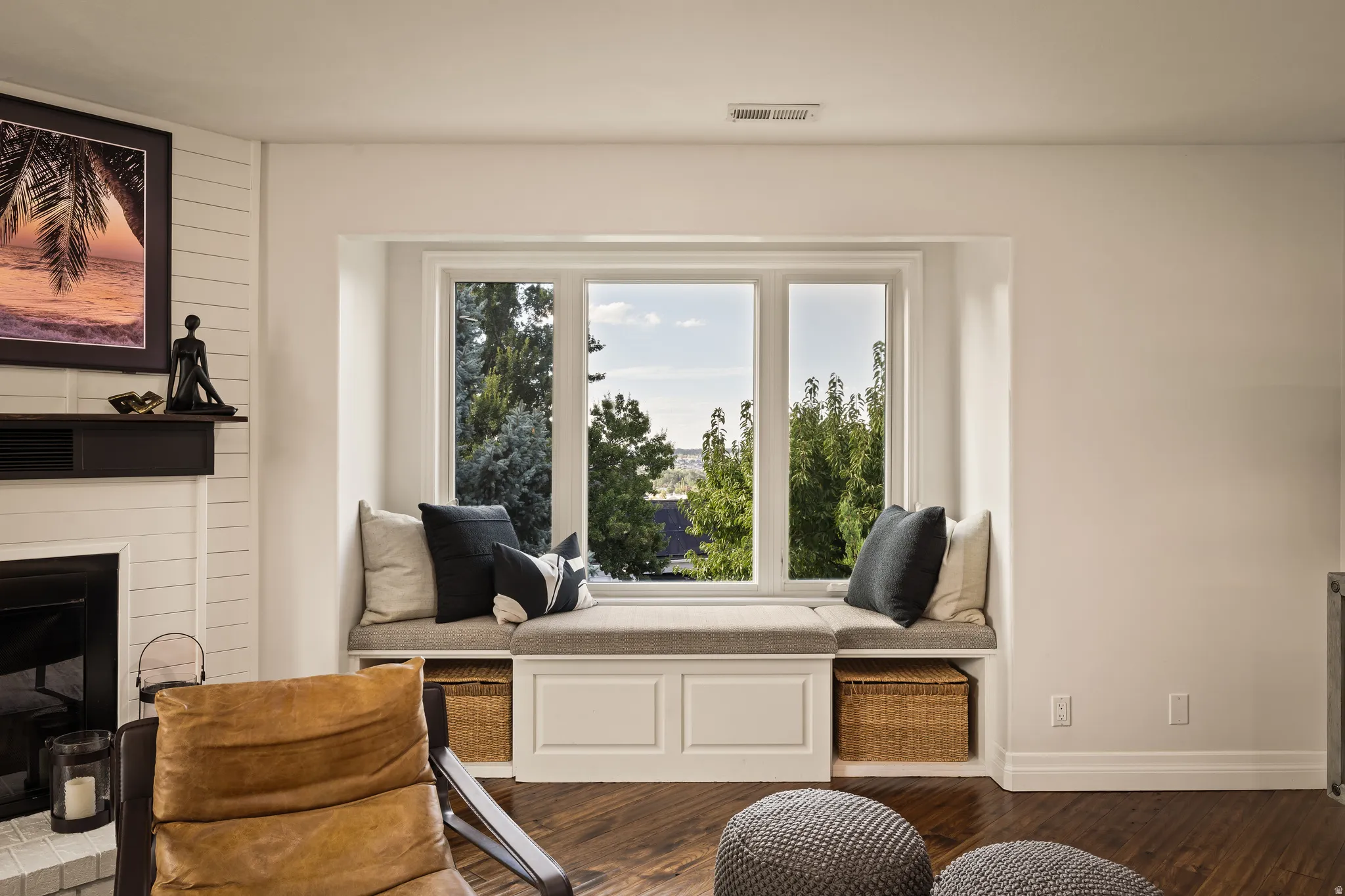 Window seat with built-in storage, wood-finish flooring, and white trim