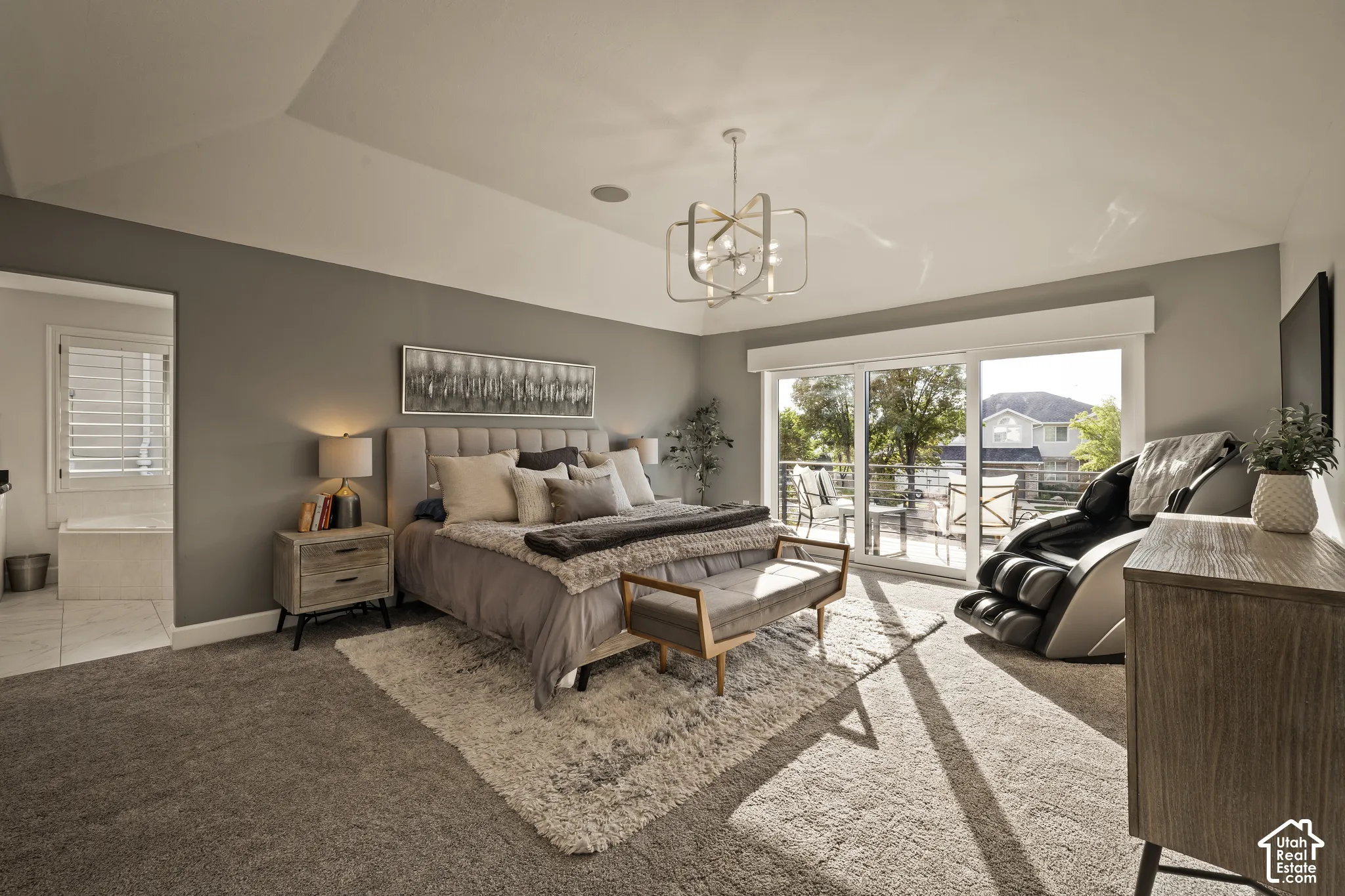 Tray ceiling with recessed lighting, modern chandelier, wall-to-wall carpeting, sliding glass door to exterior, and an en-suite bathroom with a built-in tub