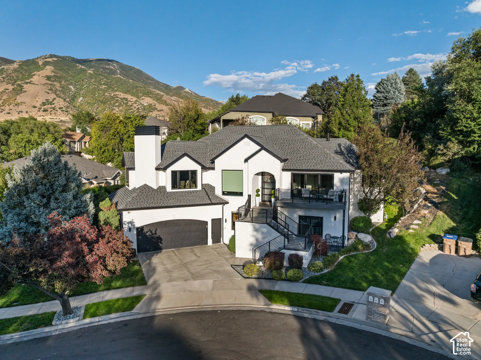 Modern exterior with white stucco and black trim, a multi-level deck, an integrated two-car garage, and a steeply pitched roof
