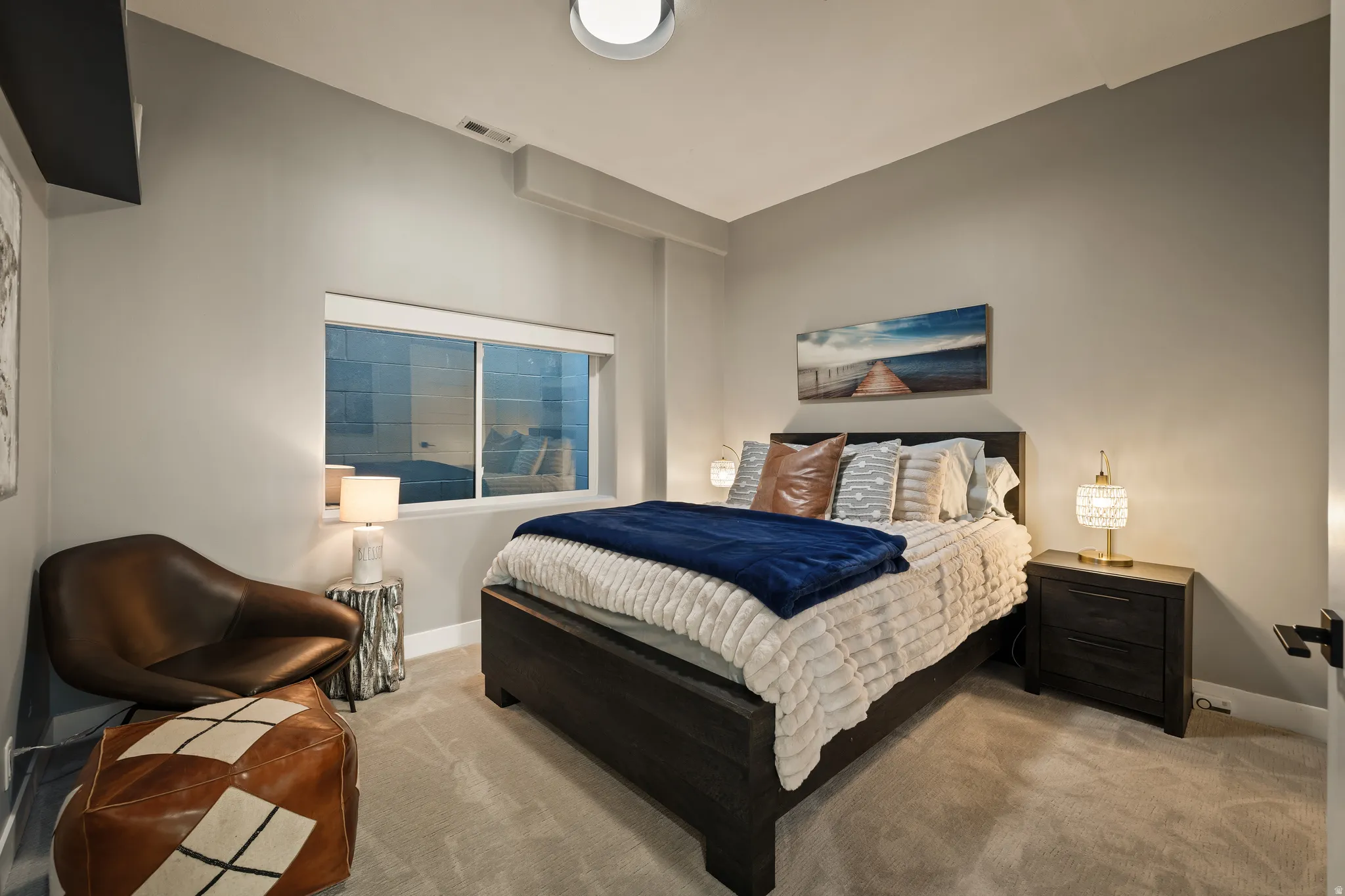 Carpeted room featuring a window with a white frame, a dark wood-finish bed frame, and a dark wood-finish nightstand