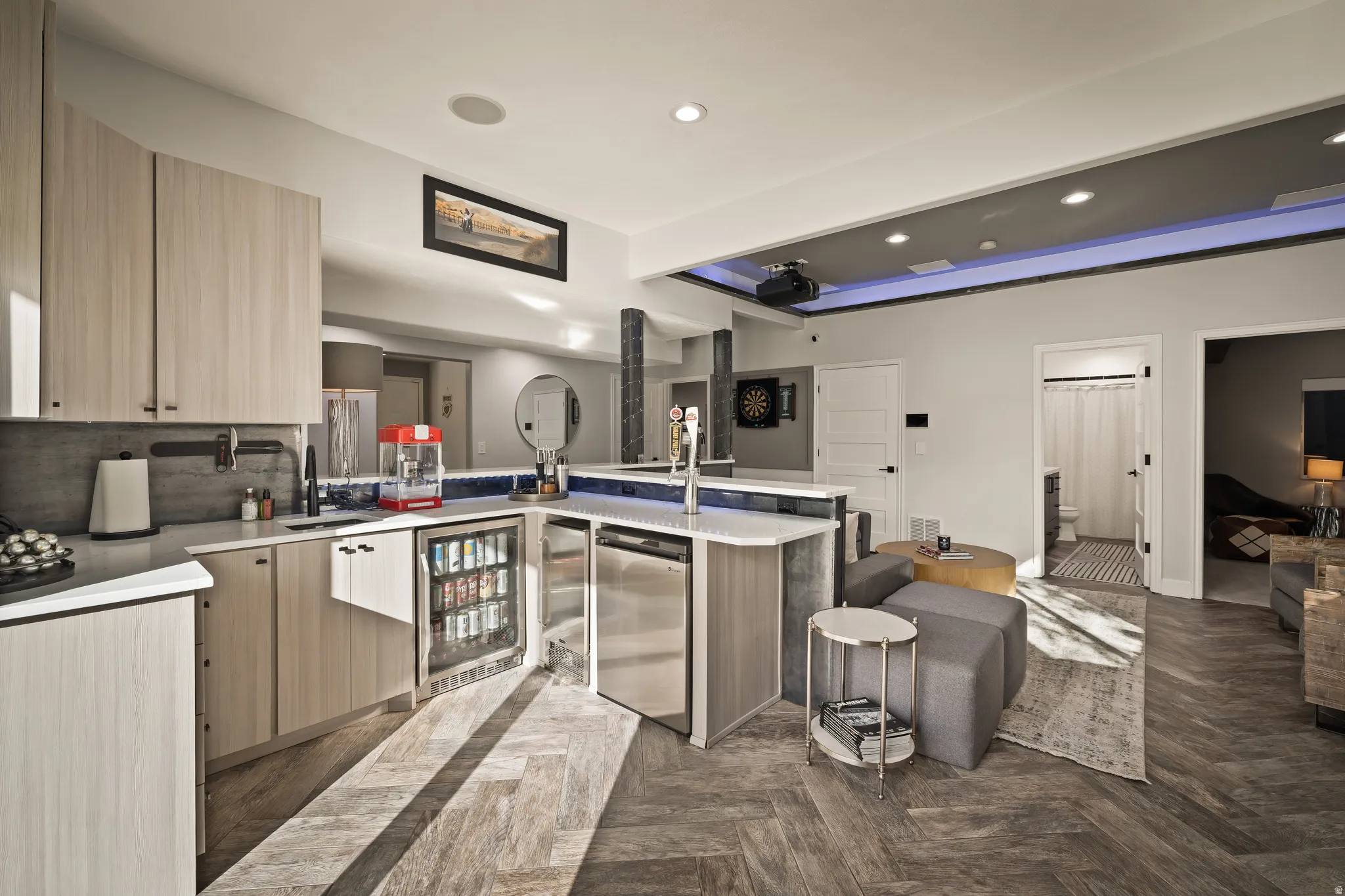 Contemporary kitchenette with light wood-finish cabinetry, integrated beverage refrigerator, and stainless steel dishwasher