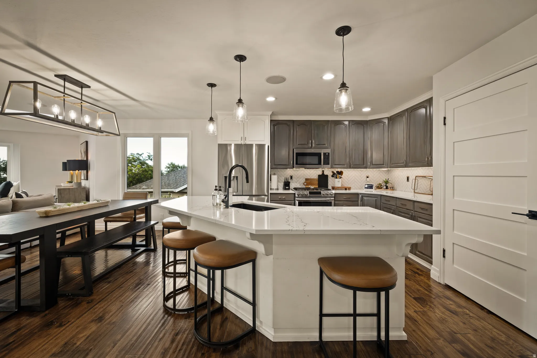 Gourmet kitchen with a large island, stainless steel appliances, wood-finish flooring, and pendant lighting