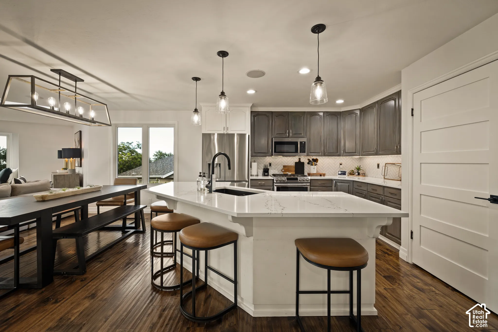 Gourmet kitchen with a large island, stainless steel appliances, wood-finish flooring, and pendant lighting