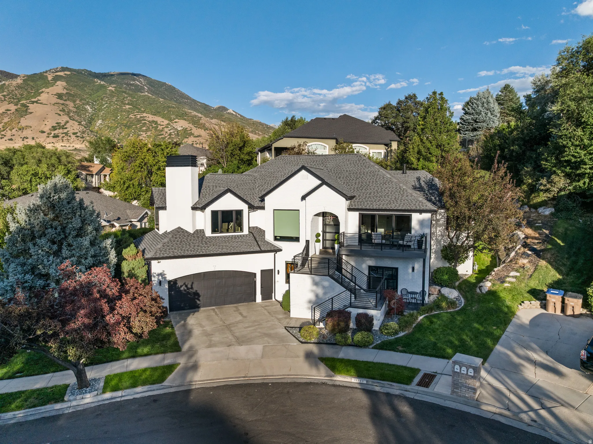 Modern exterior with white stucco and black trim, a multi-level deck, an integrated two-car garage, and a steeply pitched roof
