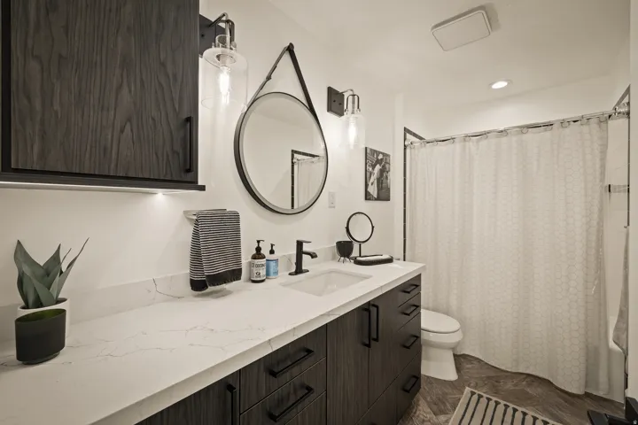 Modern vanity with a rectangular undermount sink, white countertop, and dark wood-finish cabinetry