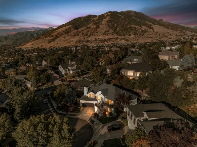 Expansive mountain backdrop, residential neighborhood setting, mature trees, multi-level dwelling, attached garage