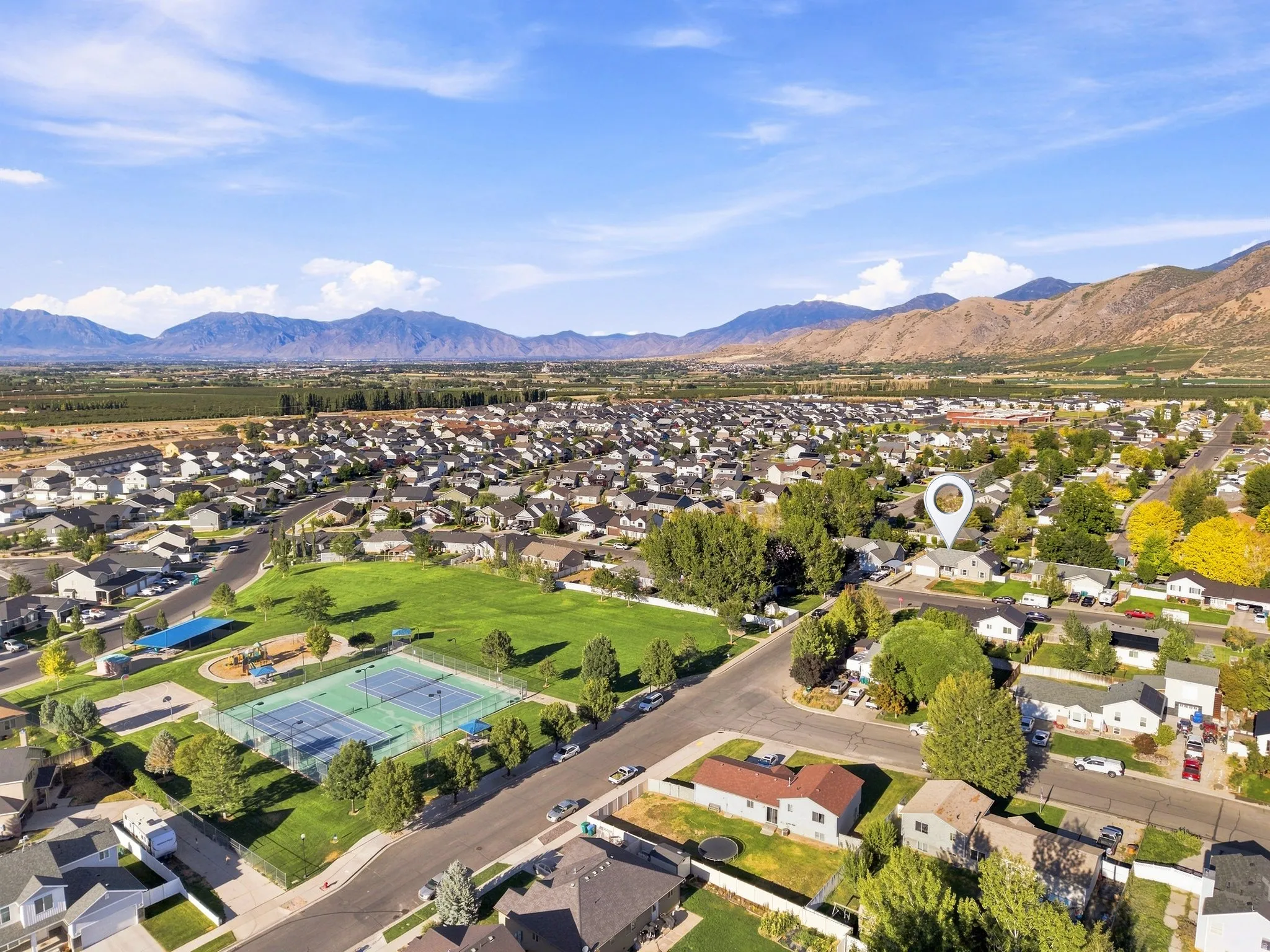 Neighborhood setting with mountainous backdrop, community green space, and tennis courts