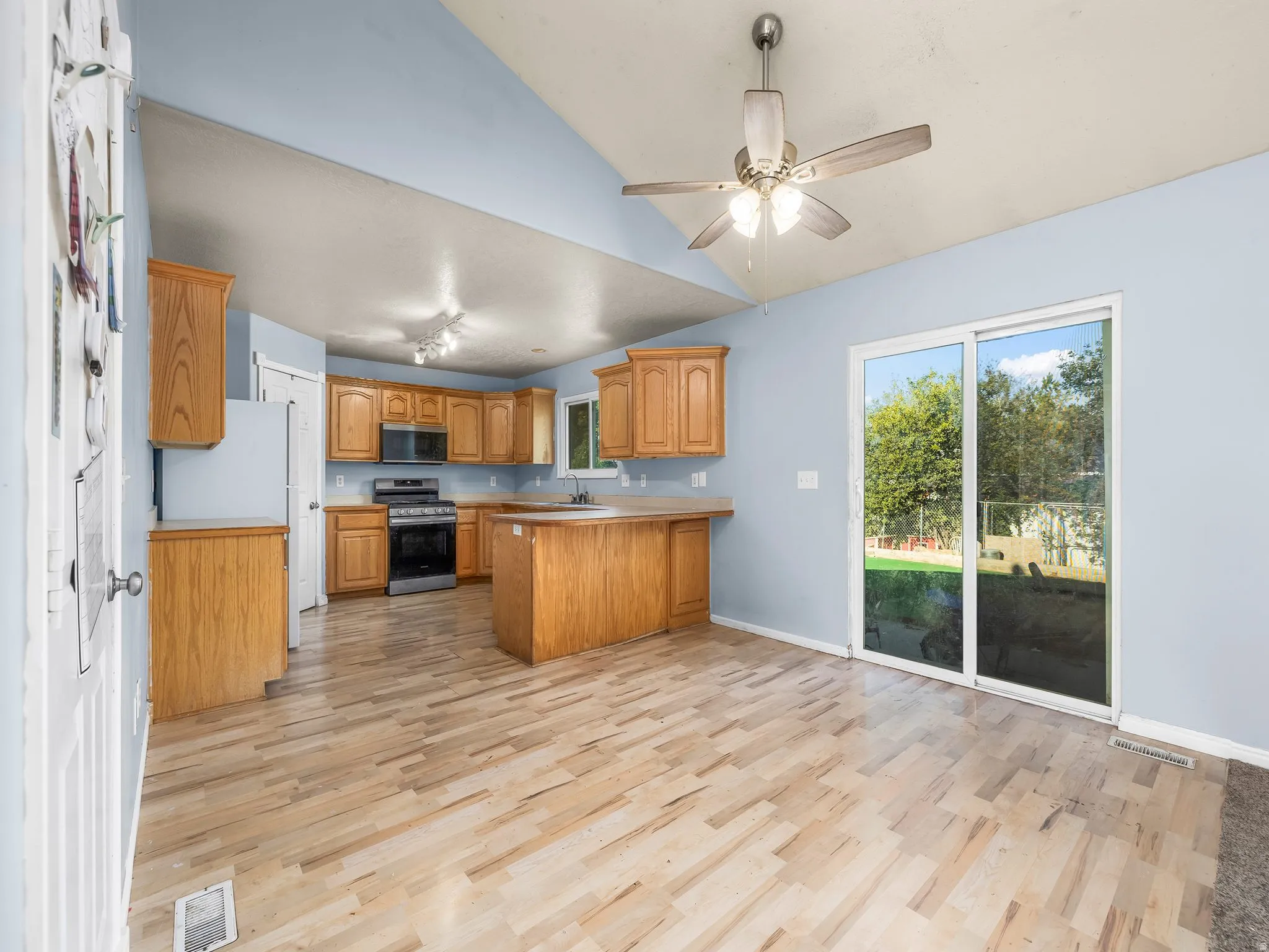 Open-concept kitchen with wood cabinetry, stainless steel range and microwave, and a breakfast bar