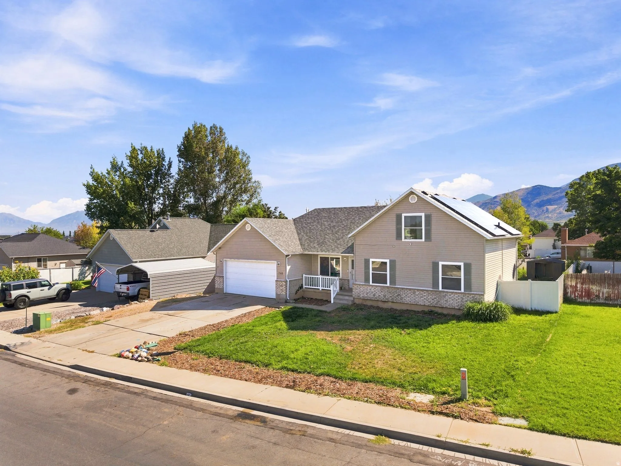 Siding exterior with a stone accent facade, attached garage, and a separate carport structure