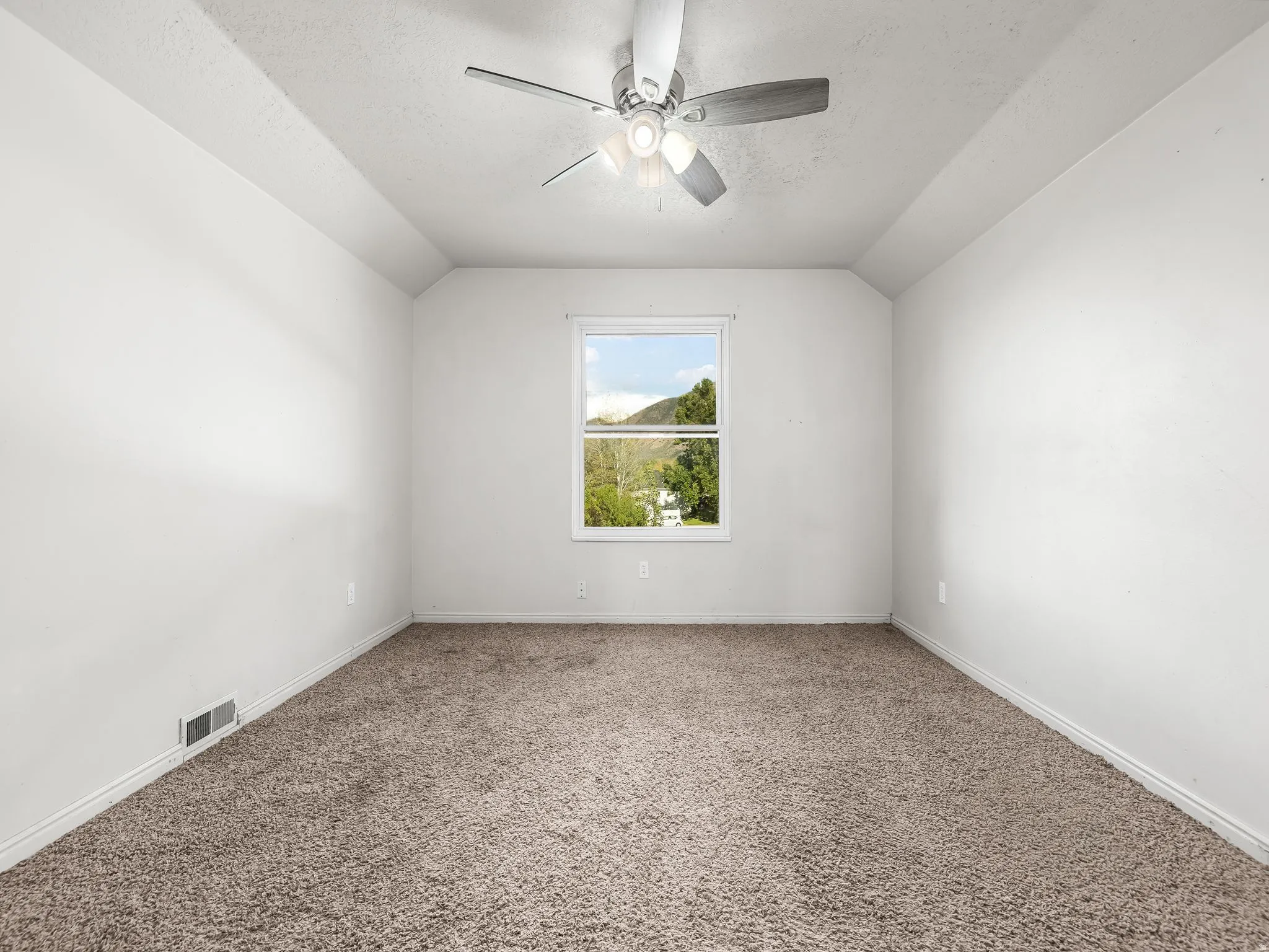 Recessed ceiling with a central window, ceiling fan with integrated lighting, and carpeted flooring