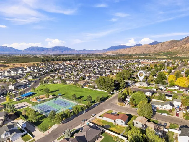 Neighborhood setting with mountainous backdrop, community green space, and tennis courts
