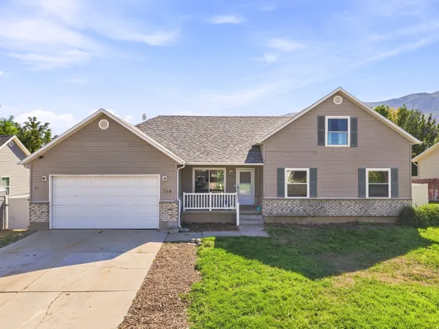 Two-story residence featuring light gray siding with a white trim, a covered porch with white railing, and a two-car garage