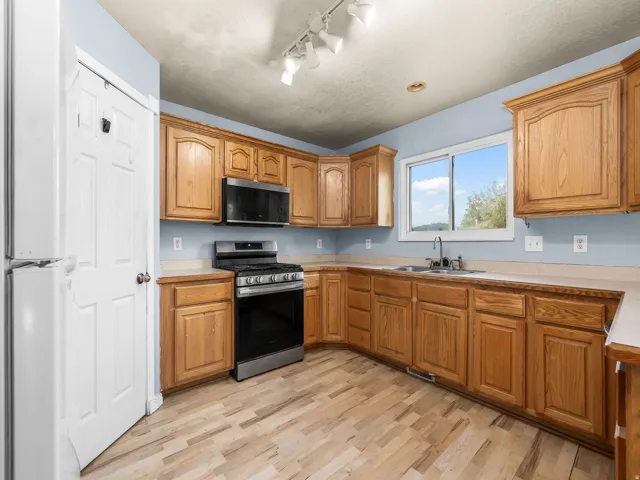 Kitchen featuring wood-finish flooring, ample wood cabinetry, and a stainless steel range with a coordinating microwave