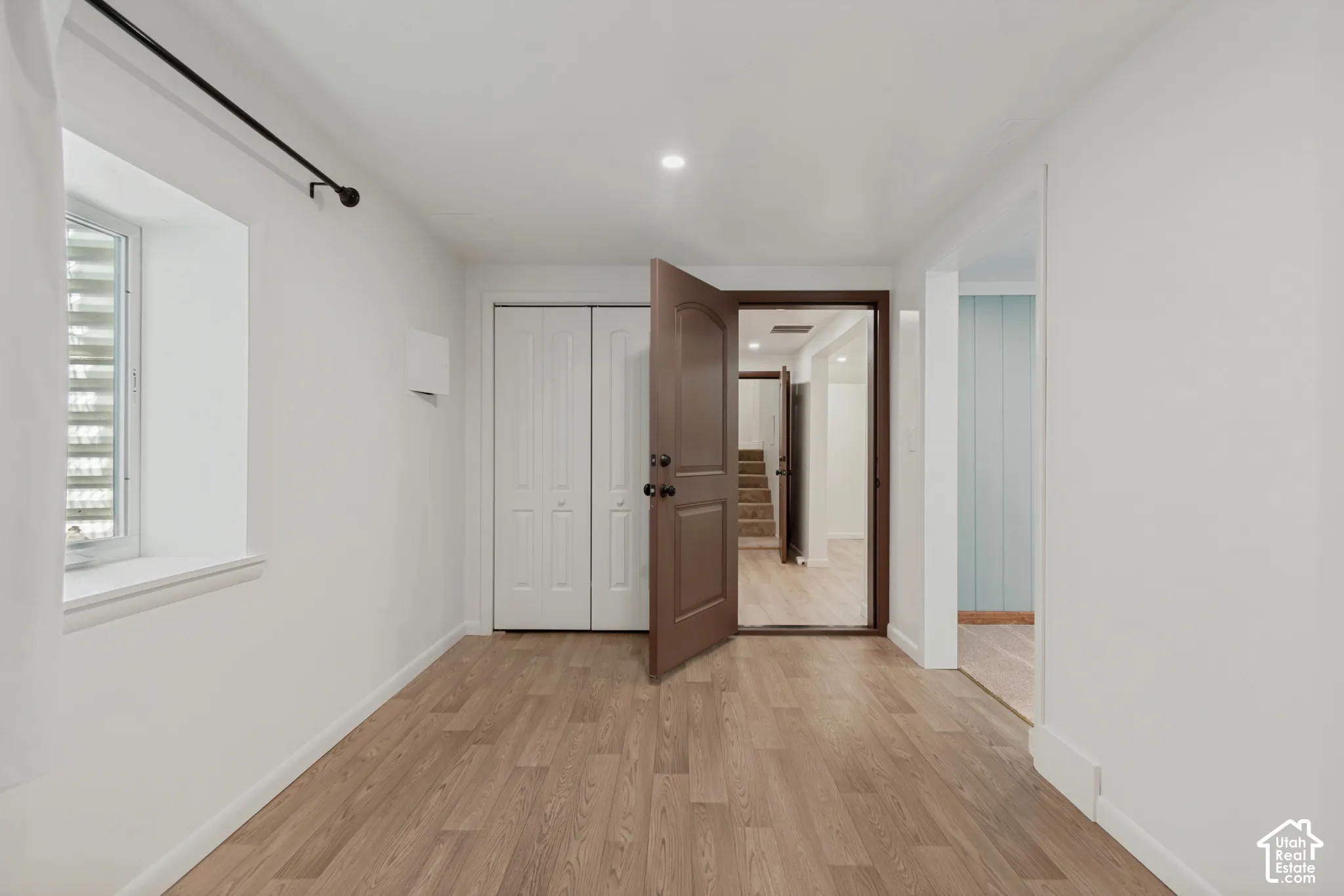 Wood-finish flooring, white walls, and a recessed window. Basement bedroom 1 with an attached den/gaming room/office