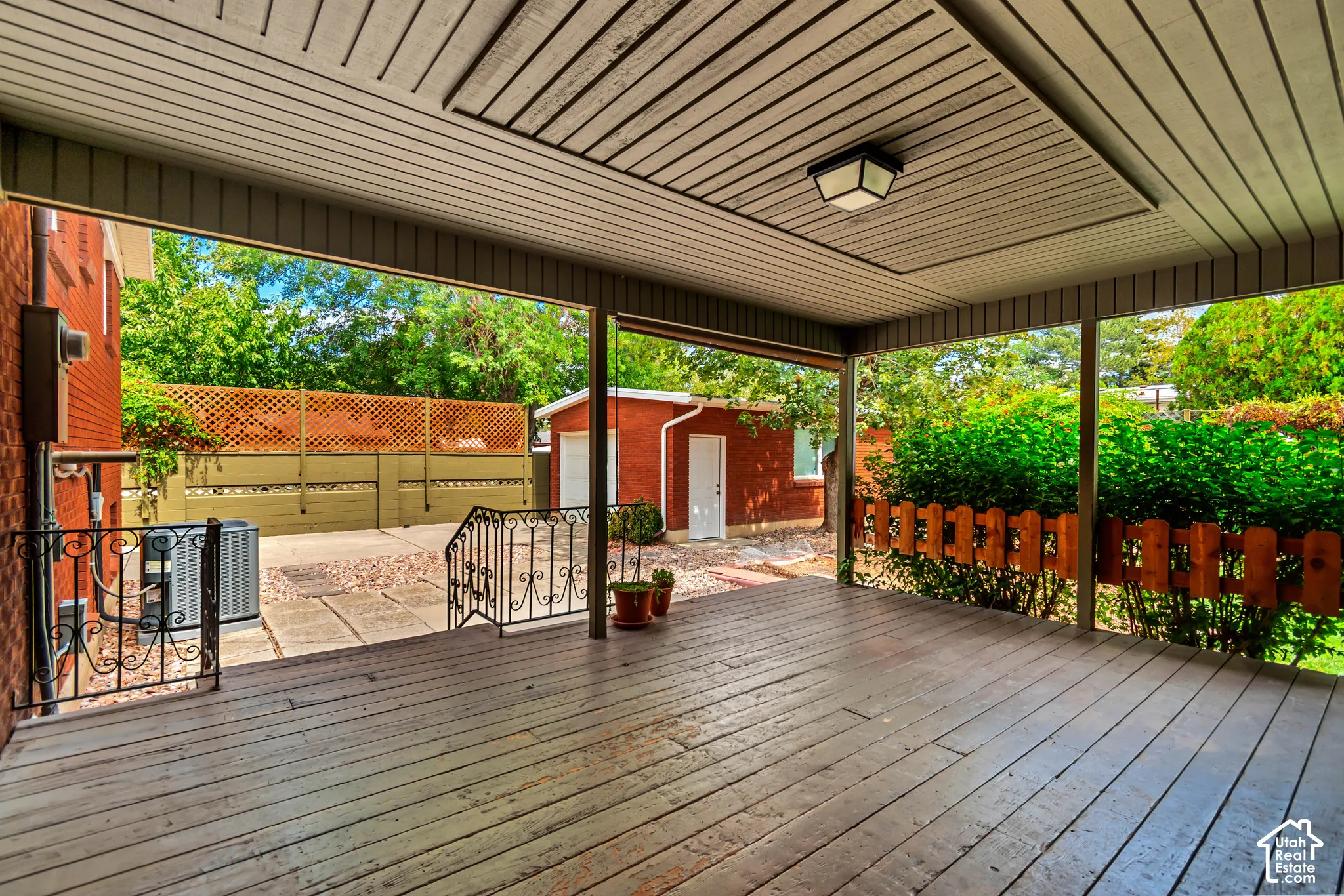 Covered deck with a wood-finish floor and ceiling, featuring an overhead light fixture