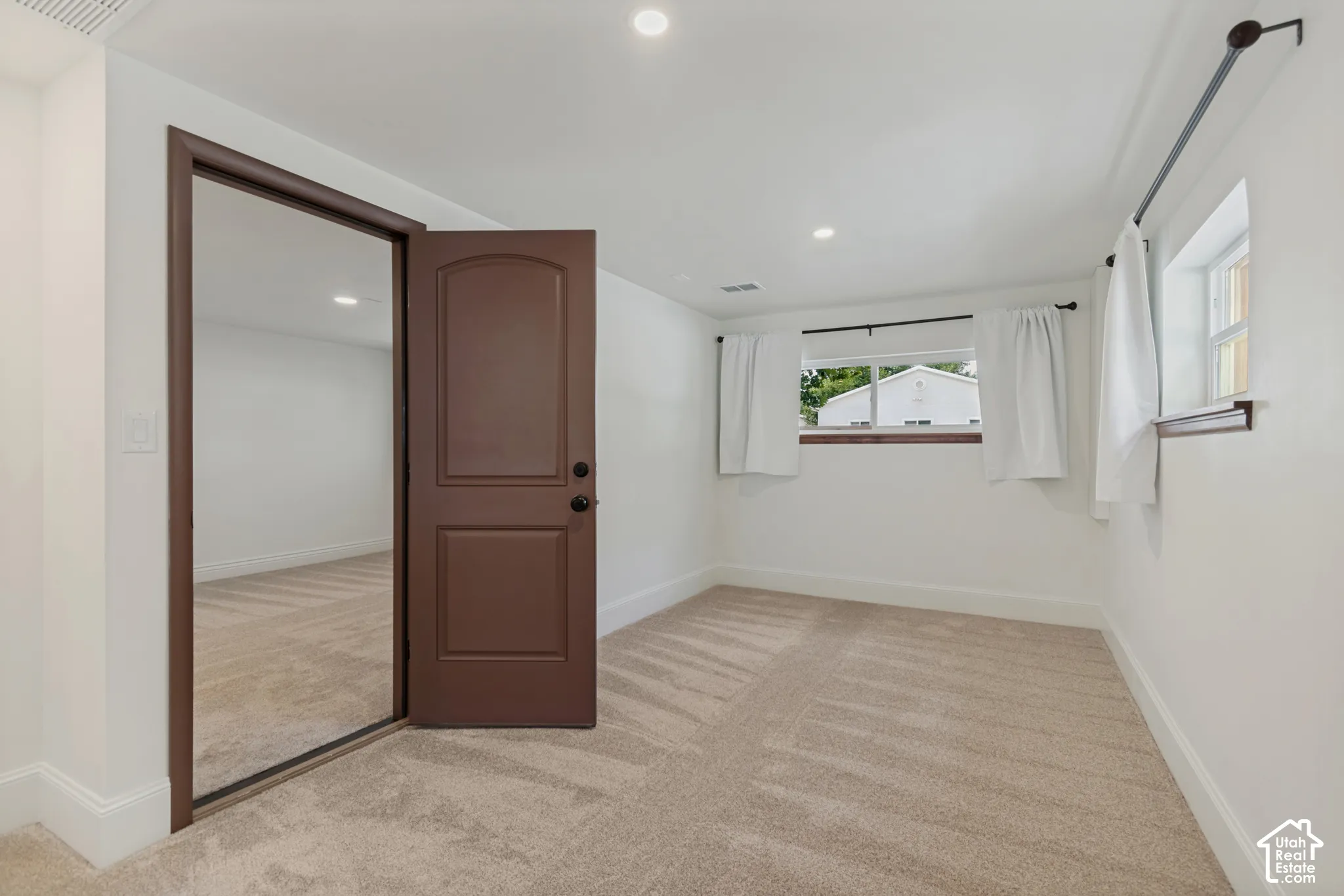 Neutral paint palette, recessed lighting, brown paneled door, two windows, and carpeting