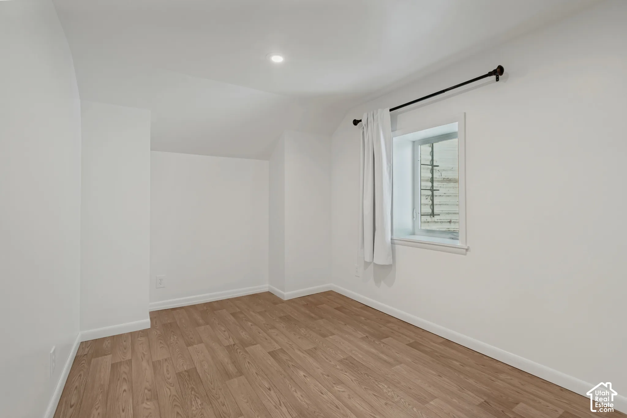Recessed ceiling lighting, wood-finish flooring, and white painted walls. Den/gaming room/office for basement bedroom 2