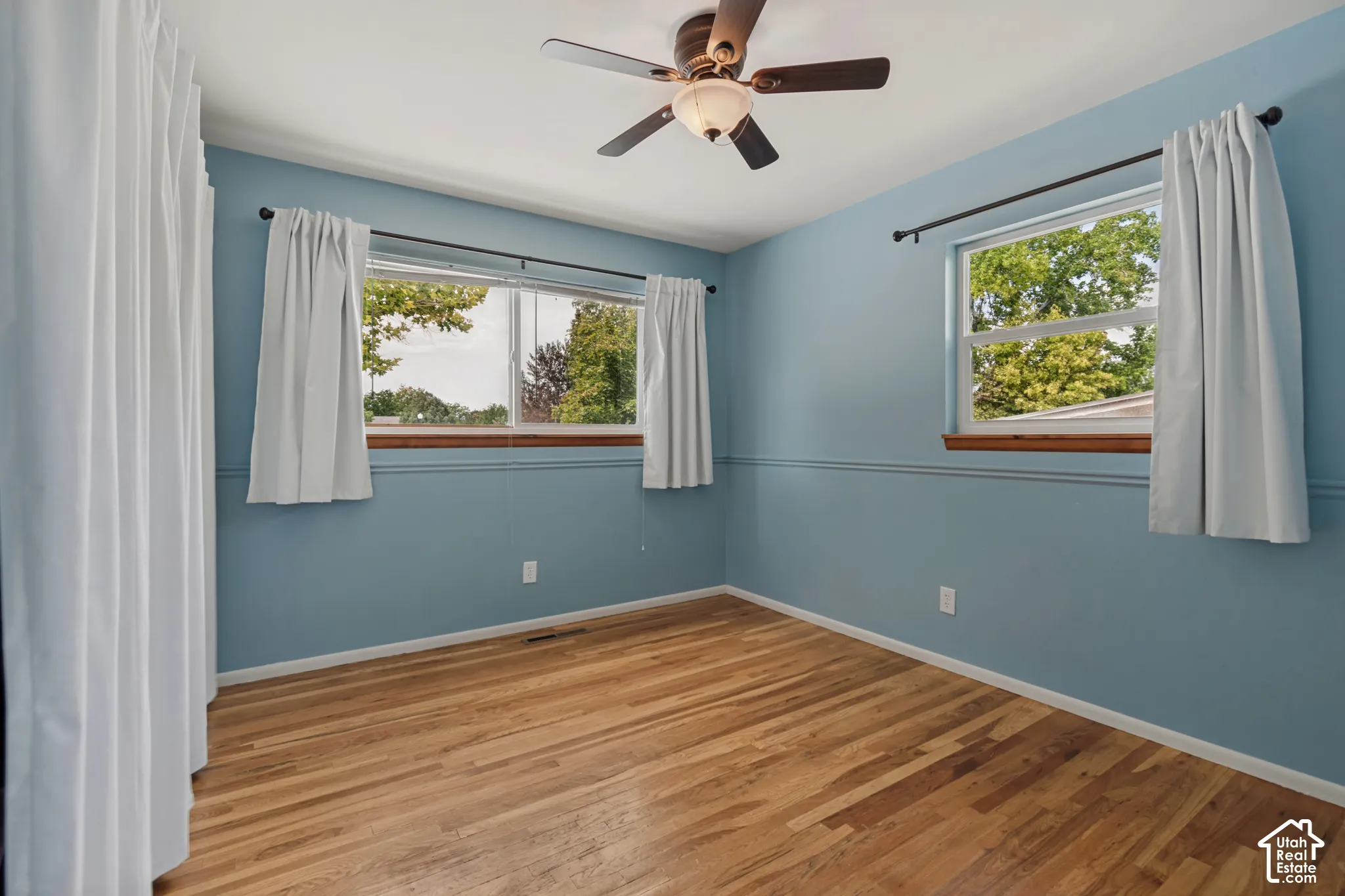 Hardwood flooring, ceiling fan with integrated lighting, and ample natural light from multiple windows