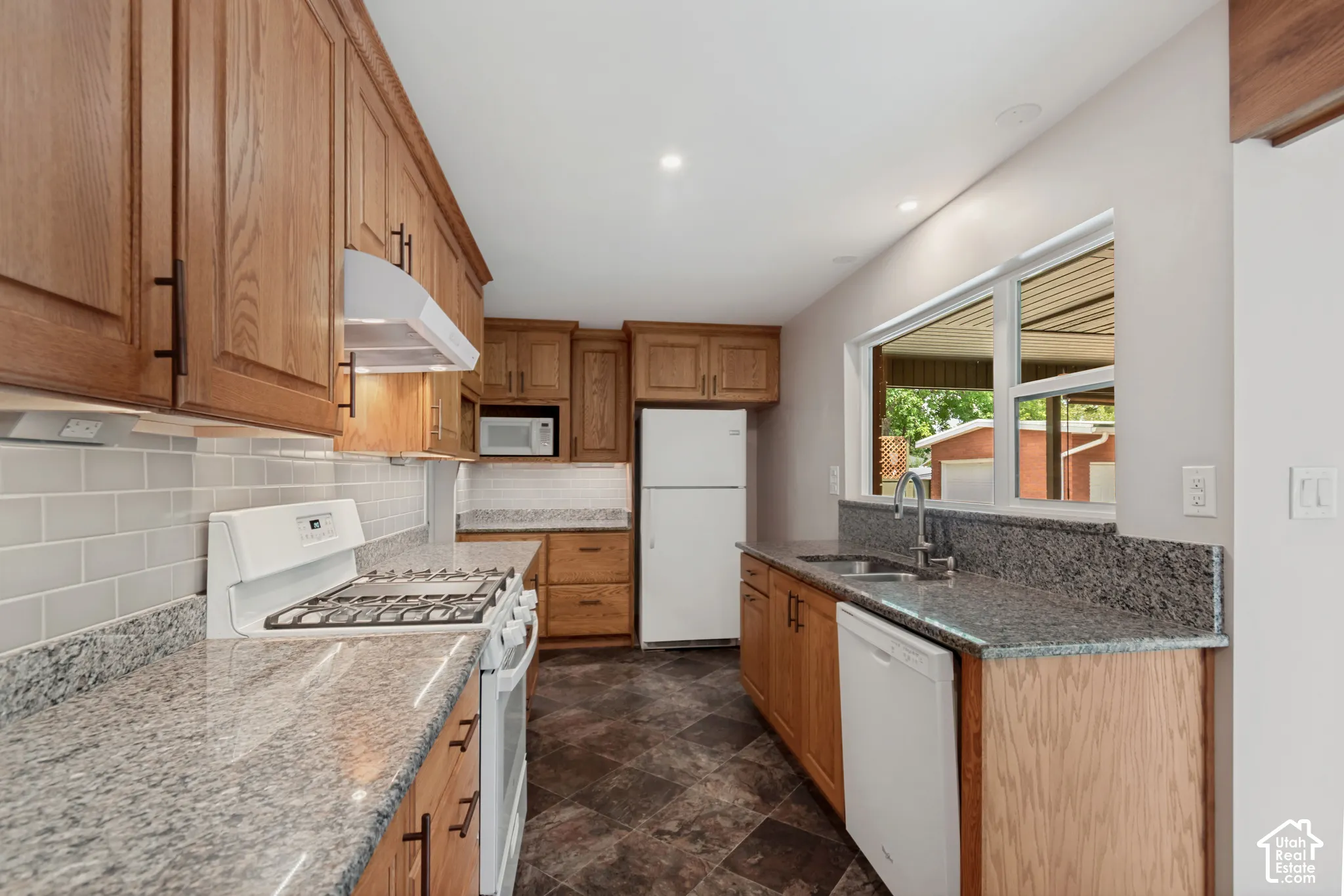 Wood cabinetry, granite countertops, subway tile backsplash and stainless sink