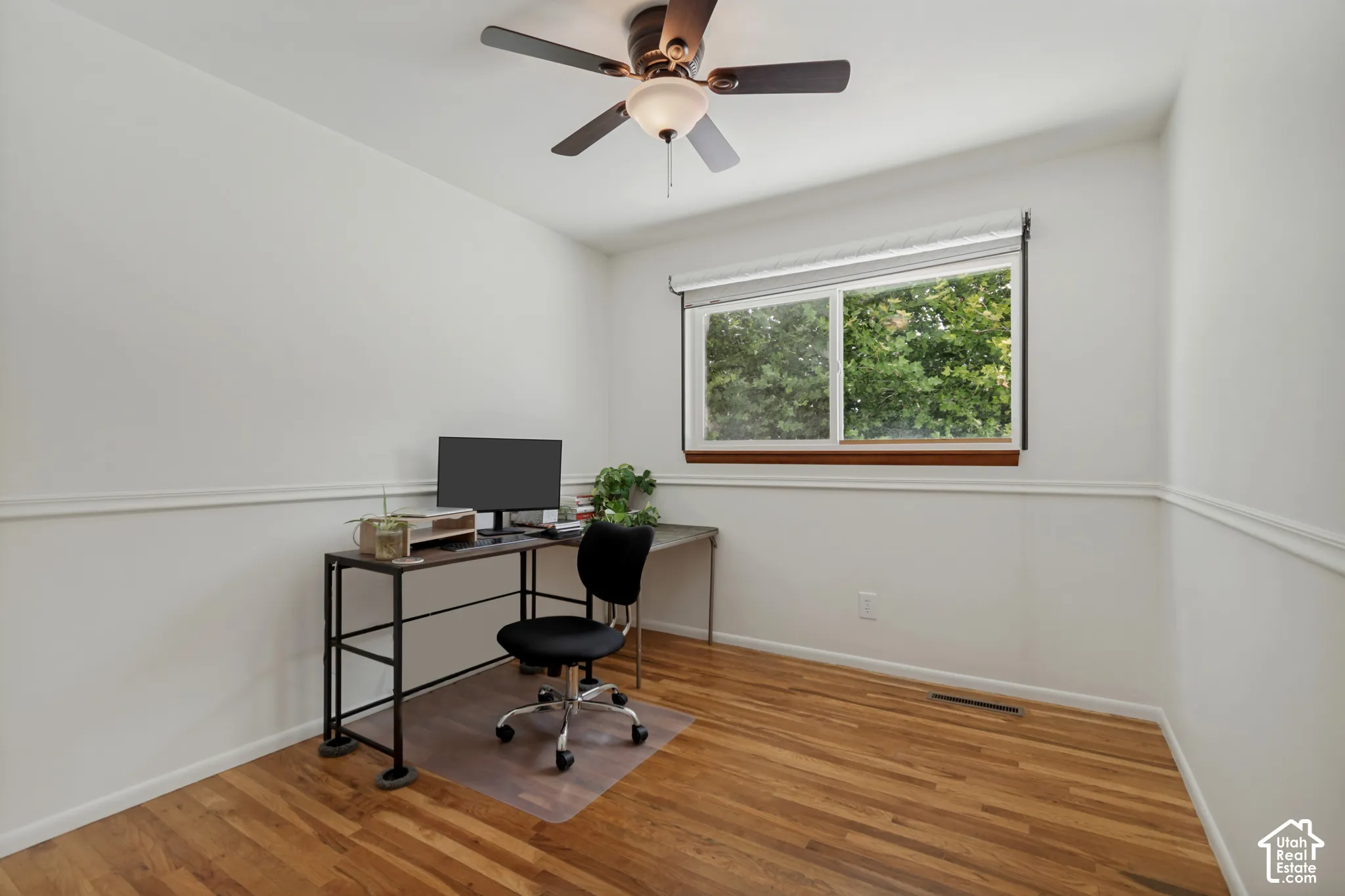 Hardwood flooring, white walls, and a multi-pane window with wood trim