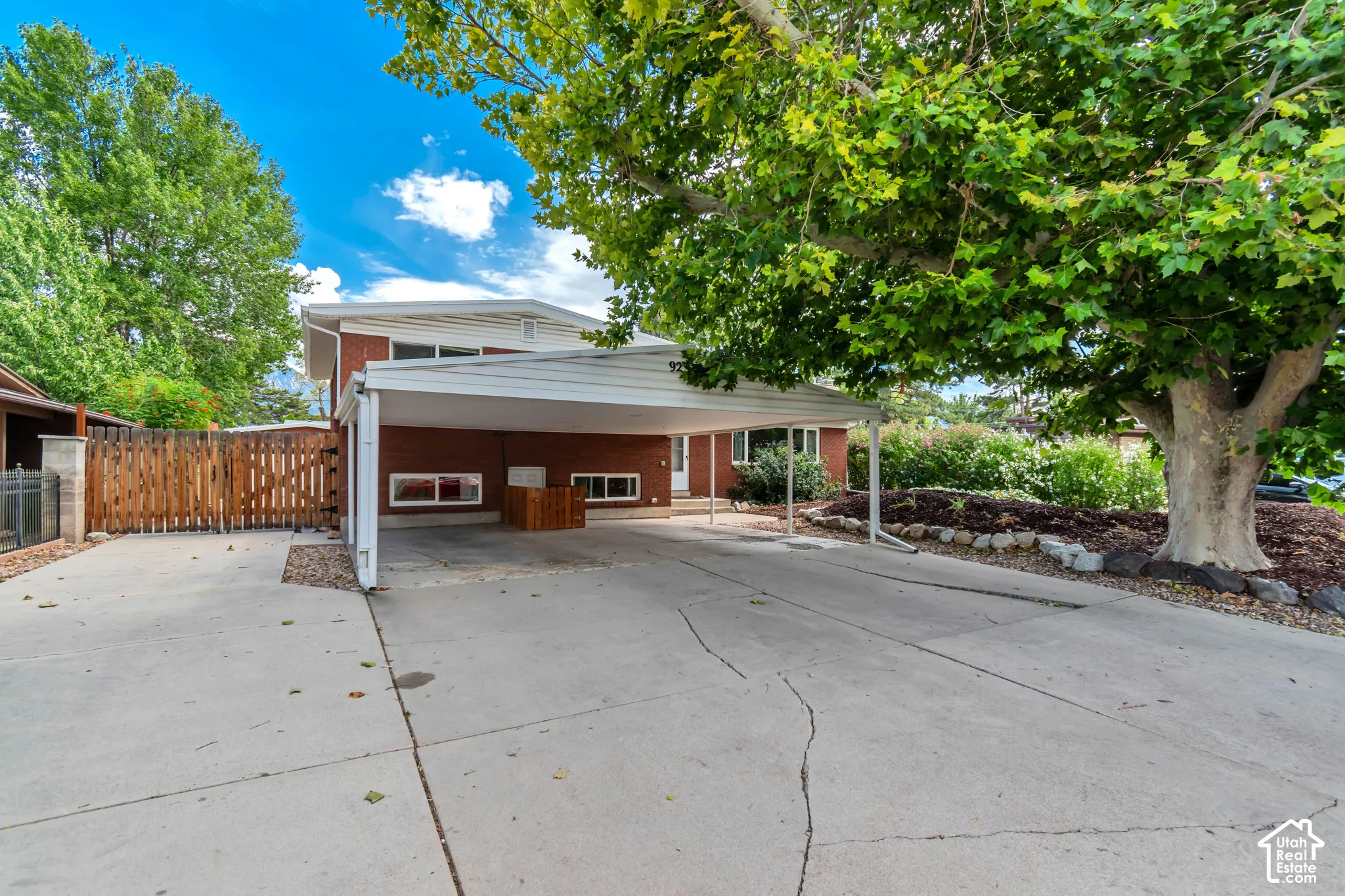Brick exterior with a white carport and a large paved driveway. RV parking available on the side of the home