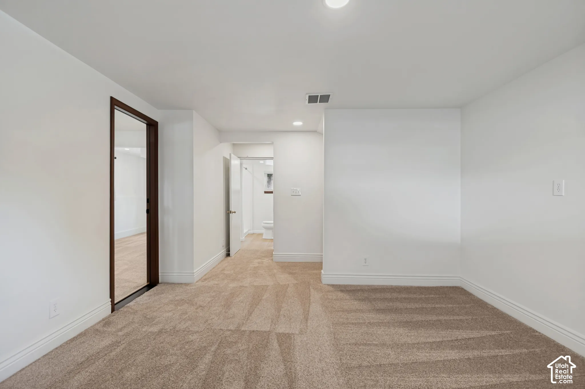 Neutral-toned carpeting, white painted walls, recessed lighting, and white baseboards