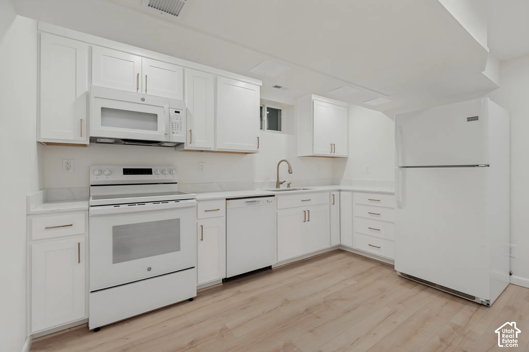 White cabinetry, stainless steel appliances, wood-finish flooring, quartz countertops