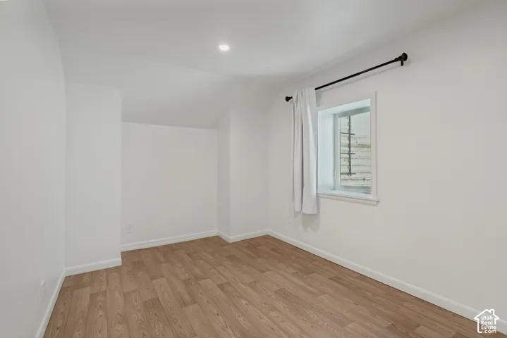 Recessed ceiling lighting, wood-finish flooring, and white painted walls. Den/gaming room/office for basement bedroom 2