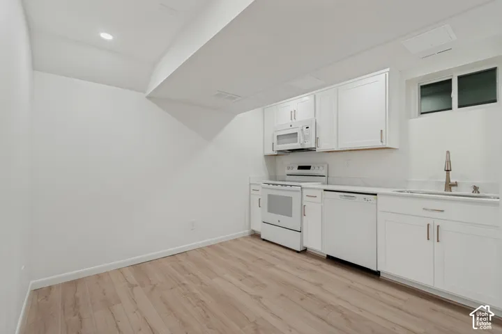 White cabinetry, stainless steel sink with pull-down faucet, white appliances, recessed lighting, and wood-finish flooring. Mother-In-Law Apartment