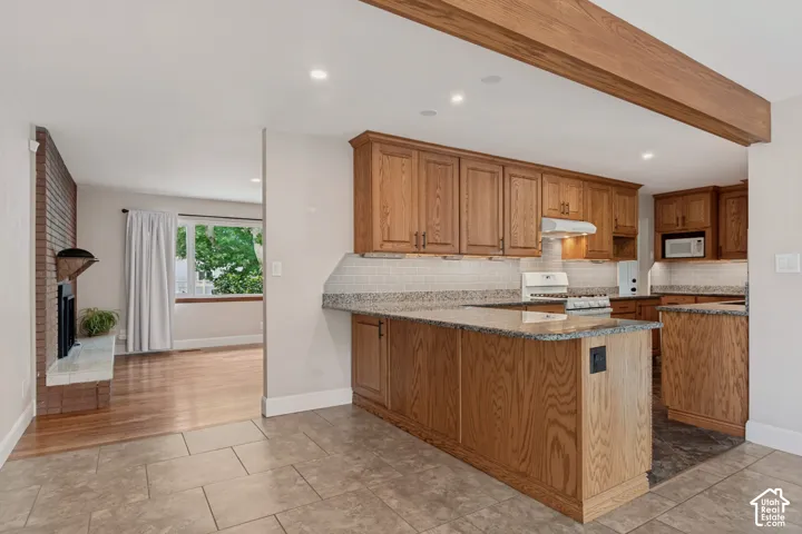 Kitchen featuring wood cabinetry, granite countertops, tile backsplash, and recessed lighting. Plenty of room to sit at the counter