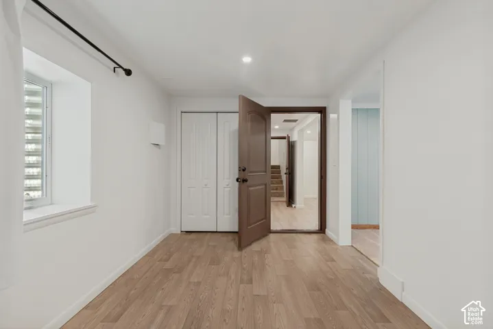 Wood-finish flooring, white walls, and a recessed window. Basement bedroom 1 with an attached den/gaming room/office