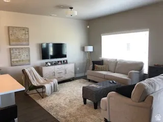 Interior room featuring wood-finish flooring, a large window, a ceiling-mounted light fixture, and neutral wall tones