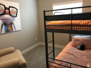Carpeted room with a window featuring a roller shade and neutral wall color