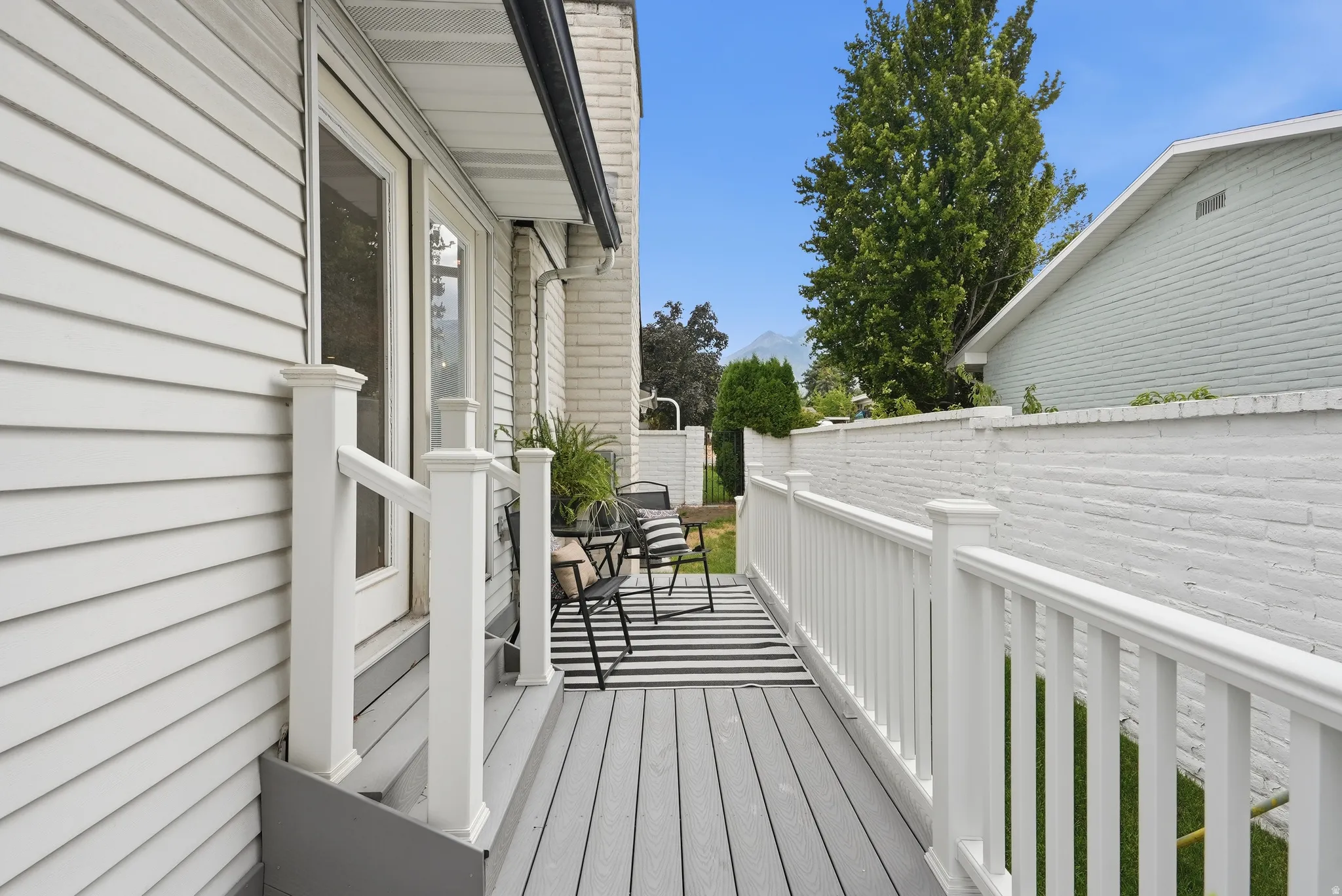 Outdoor decking featuring white railing, white siding, and a white brick privacy wall