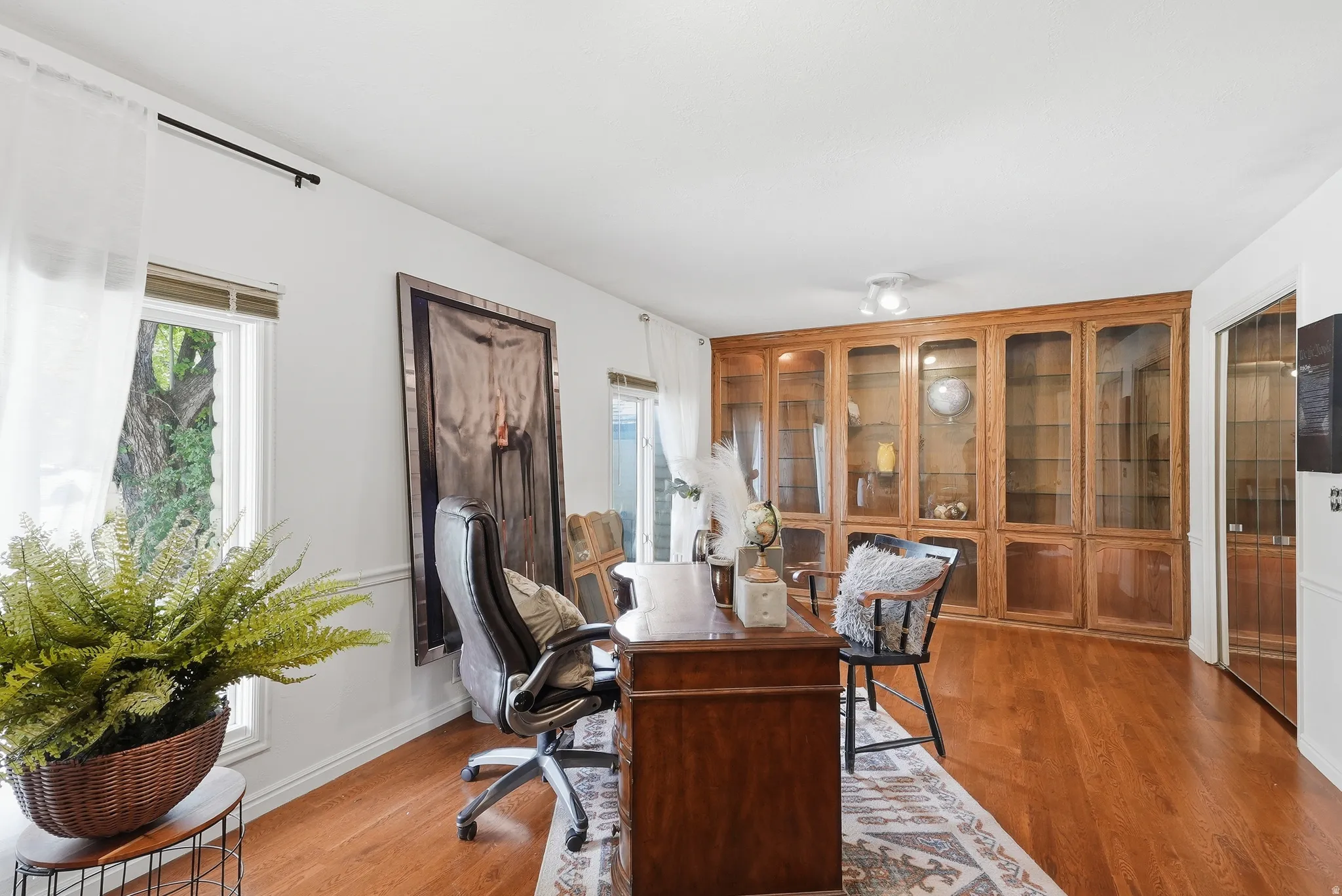 Wood-finish flooring, built-in display cabinetry with glass fronts, recessed lighting, and white window frames