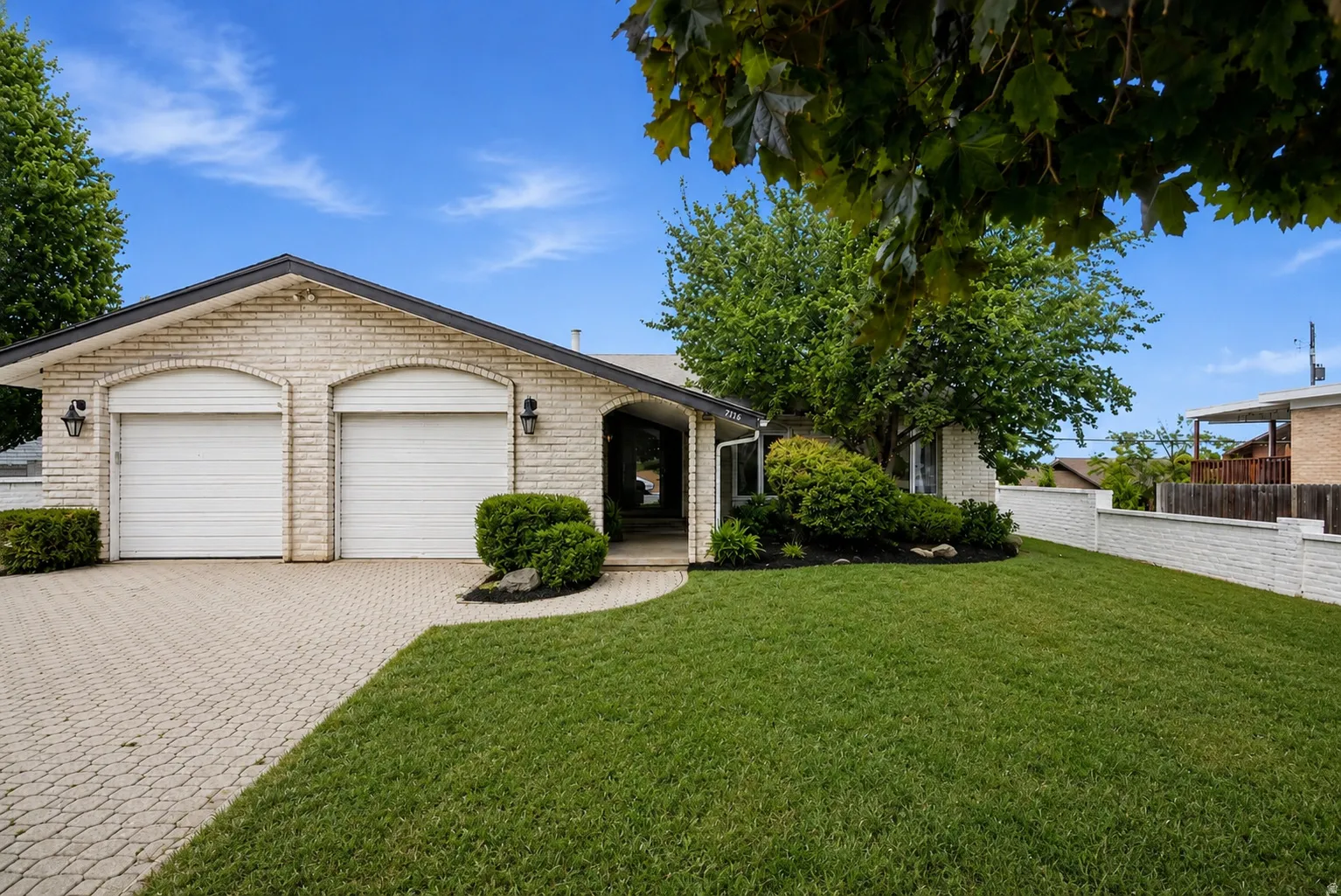 Brick exterior with a gabled roofline, dual garage bays, and a paved driveway