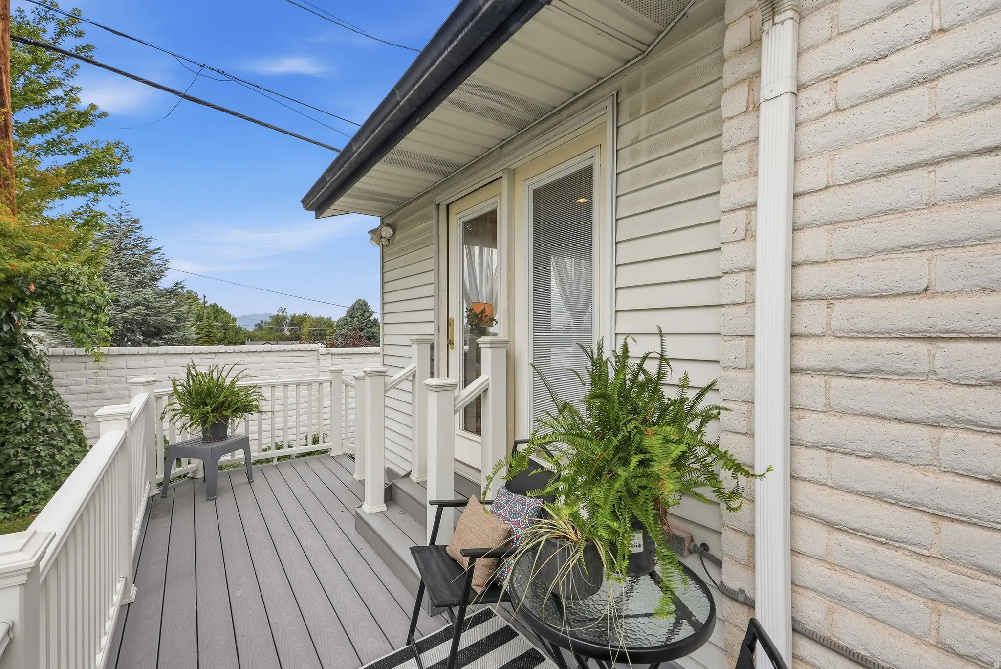 Outdoor deck with composite decking, white railing, and white siding