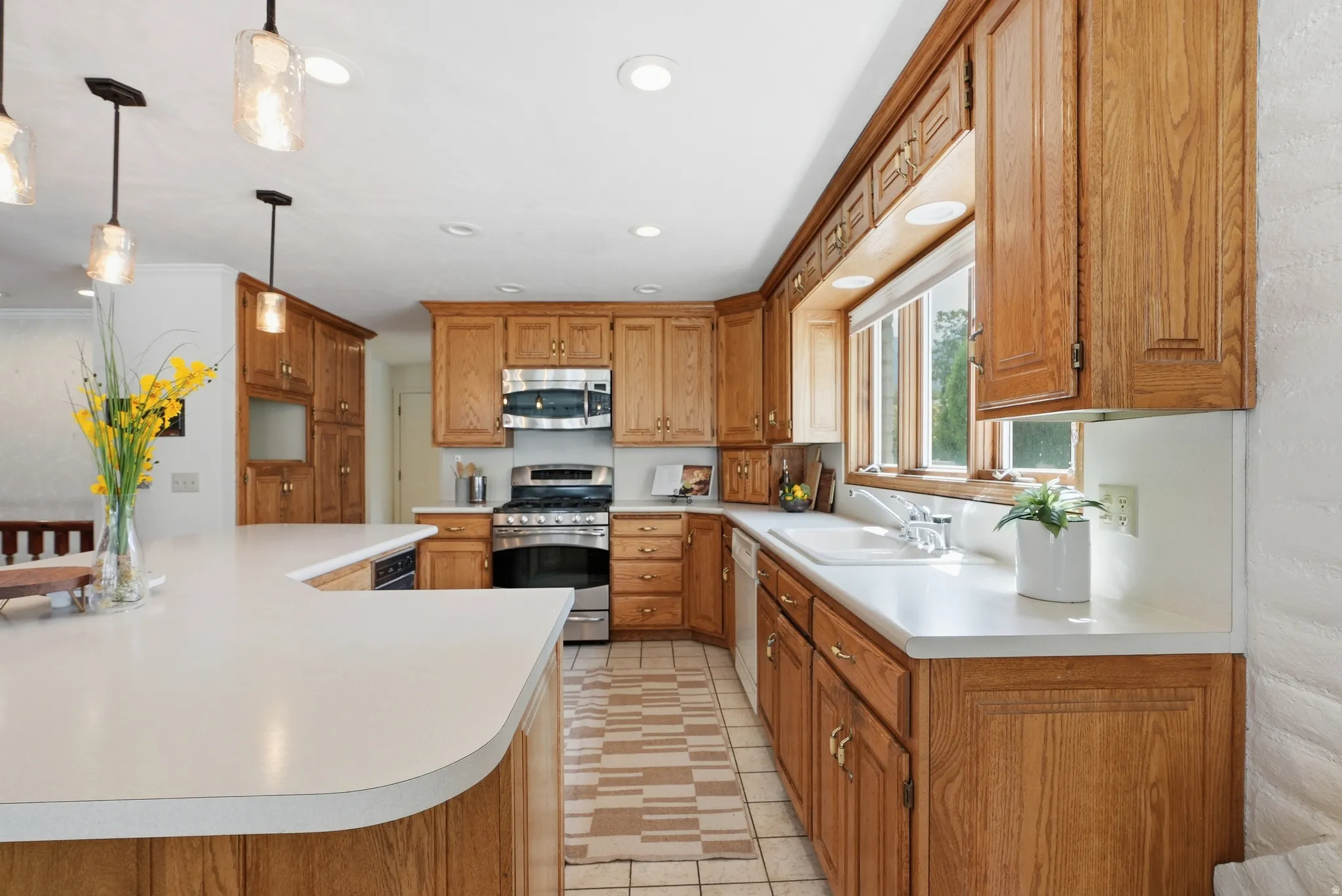 Kitchen featuring extensive wood cabinetry, white countertops, built-in stainless steel appliances, a white sink, and recessed lighting