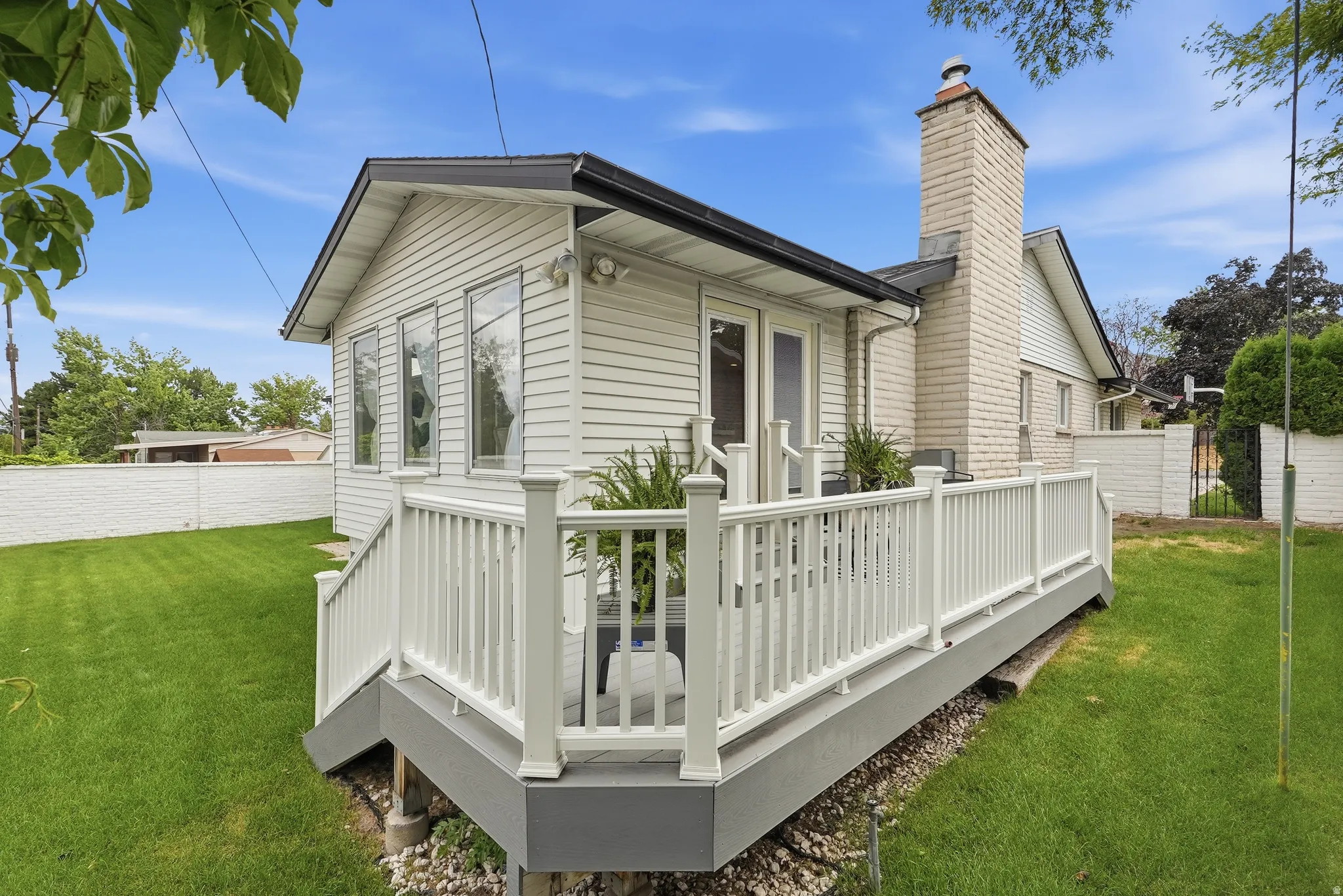 Elevated deck with white balusters, leading to an exterior extension with three vertical windows