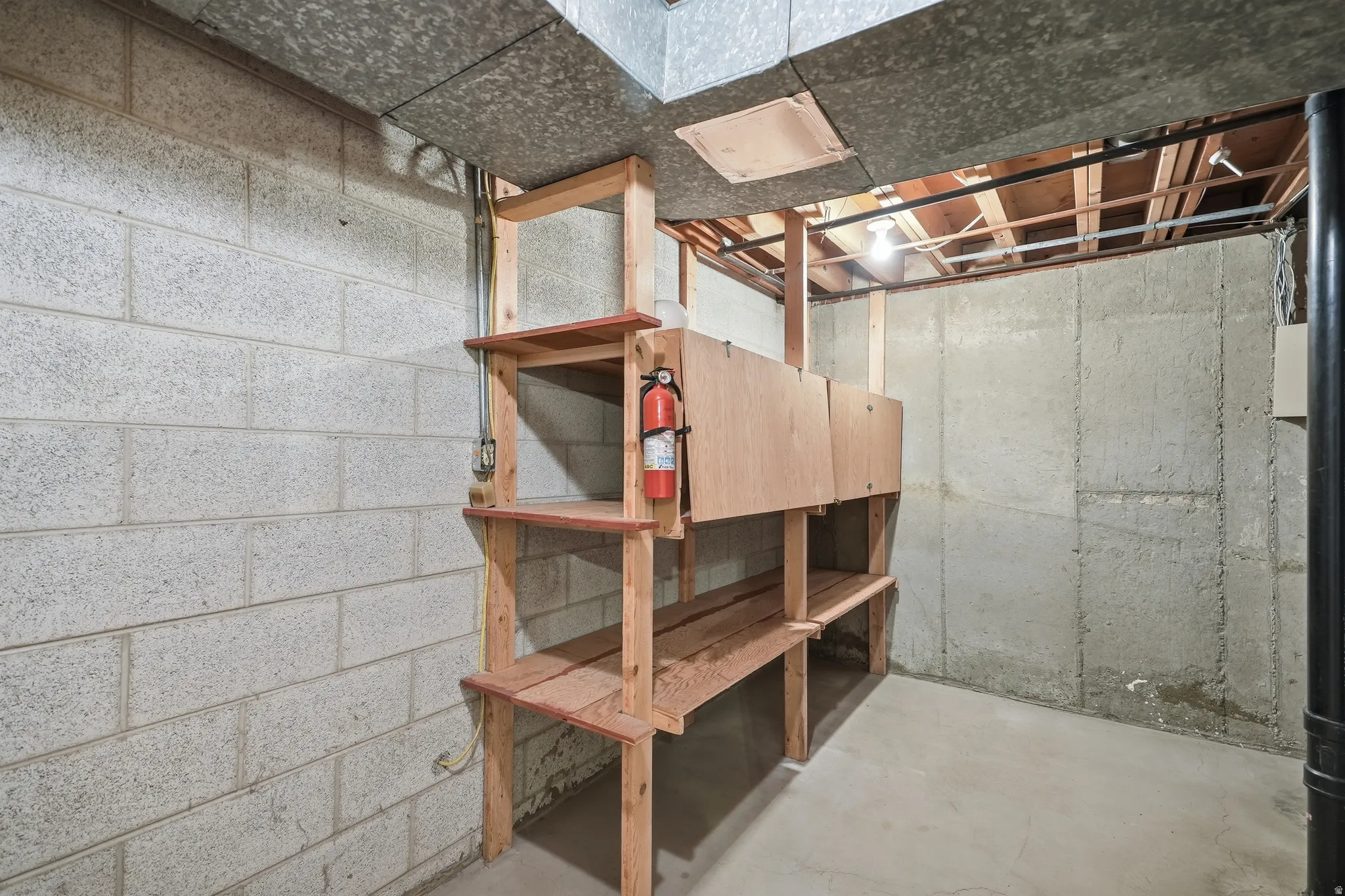 Concrete block foundation wall, built-in wooden shelving, and concrete floor