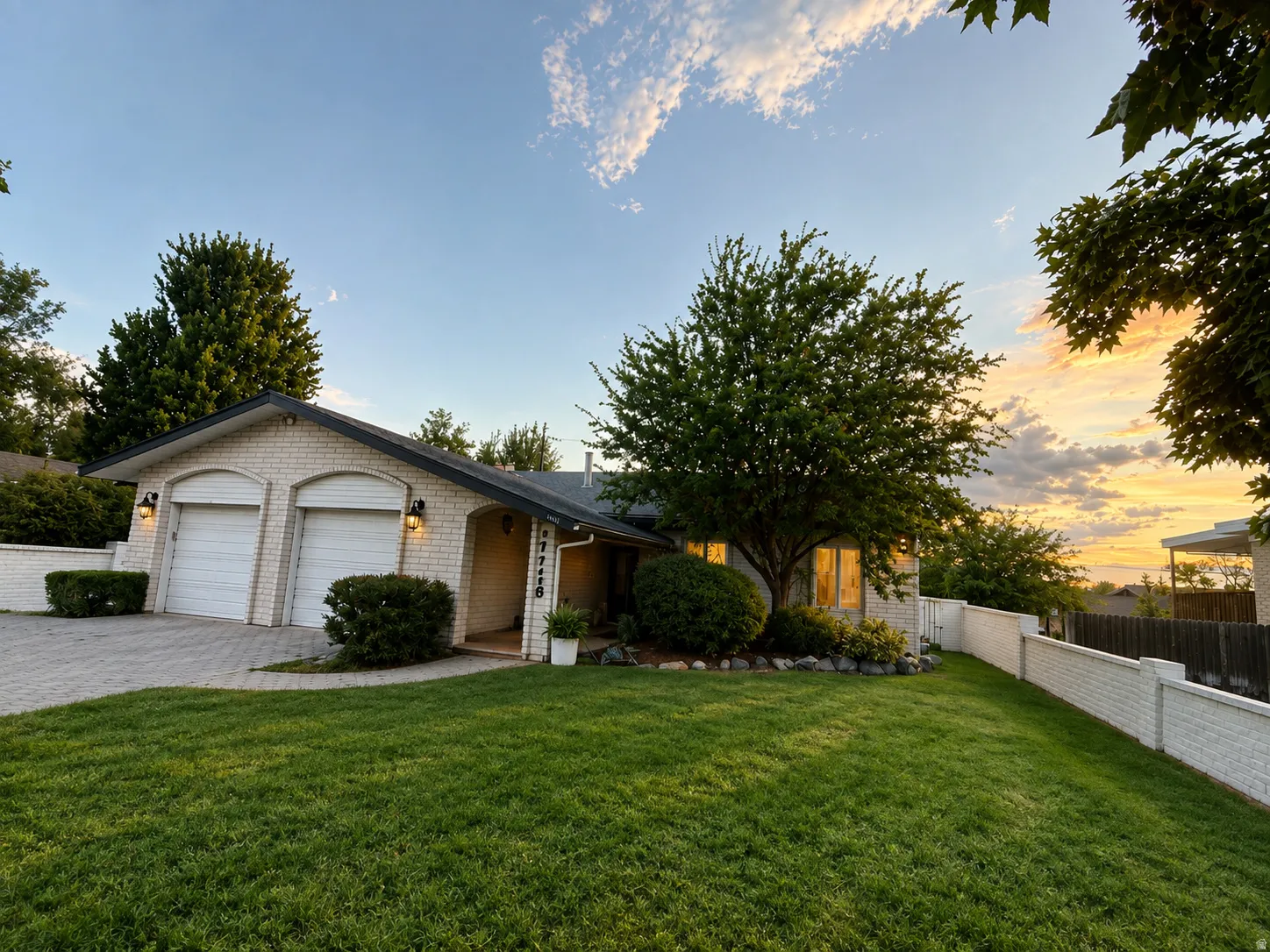 Brick exterior, attached two-car garage, brick retaining wall, mature landscaping, and a manicured lawn