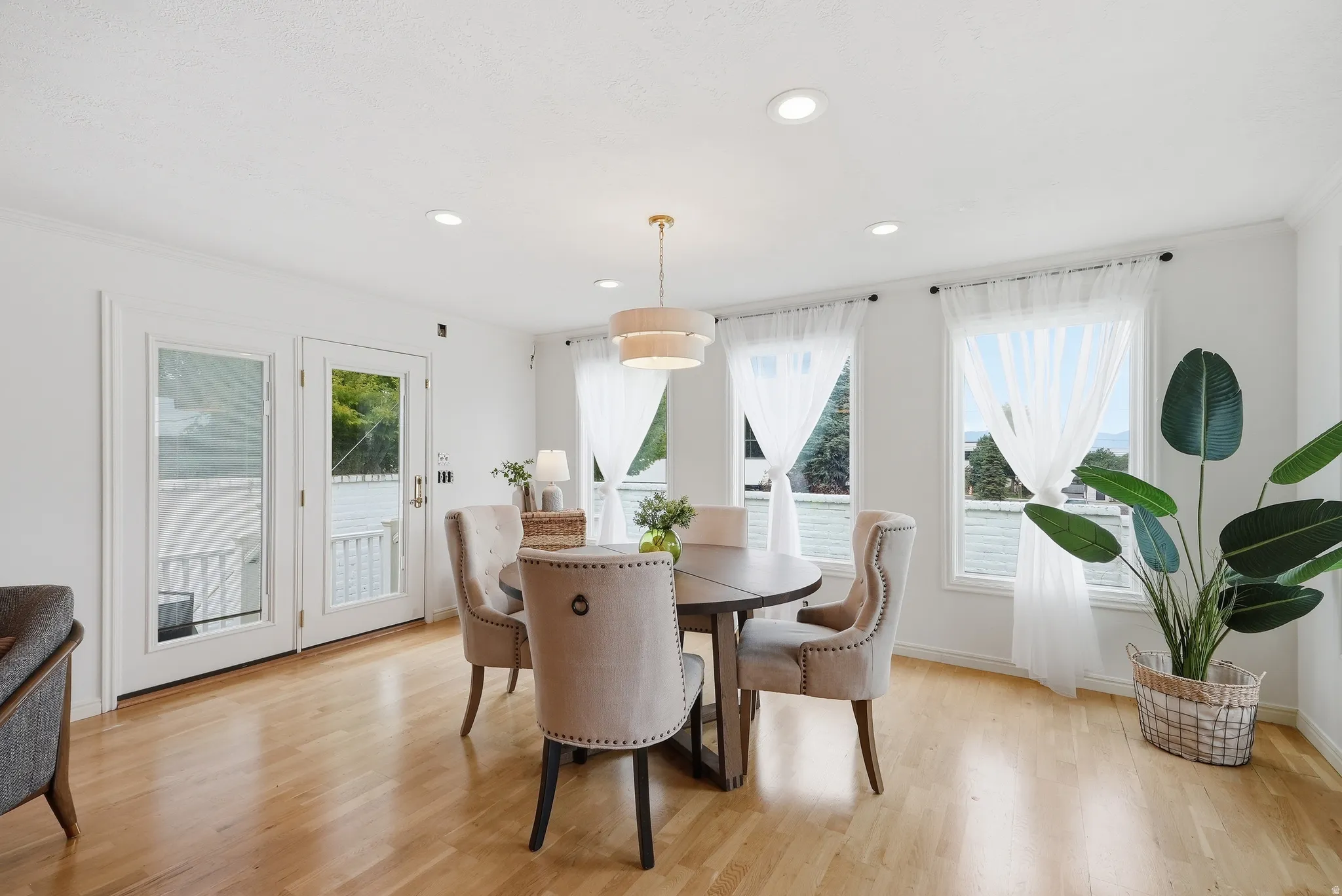 Hardwood-finish flooring, recessed lighting, and a tiered drum pendant light fixture illuminate the dining area
