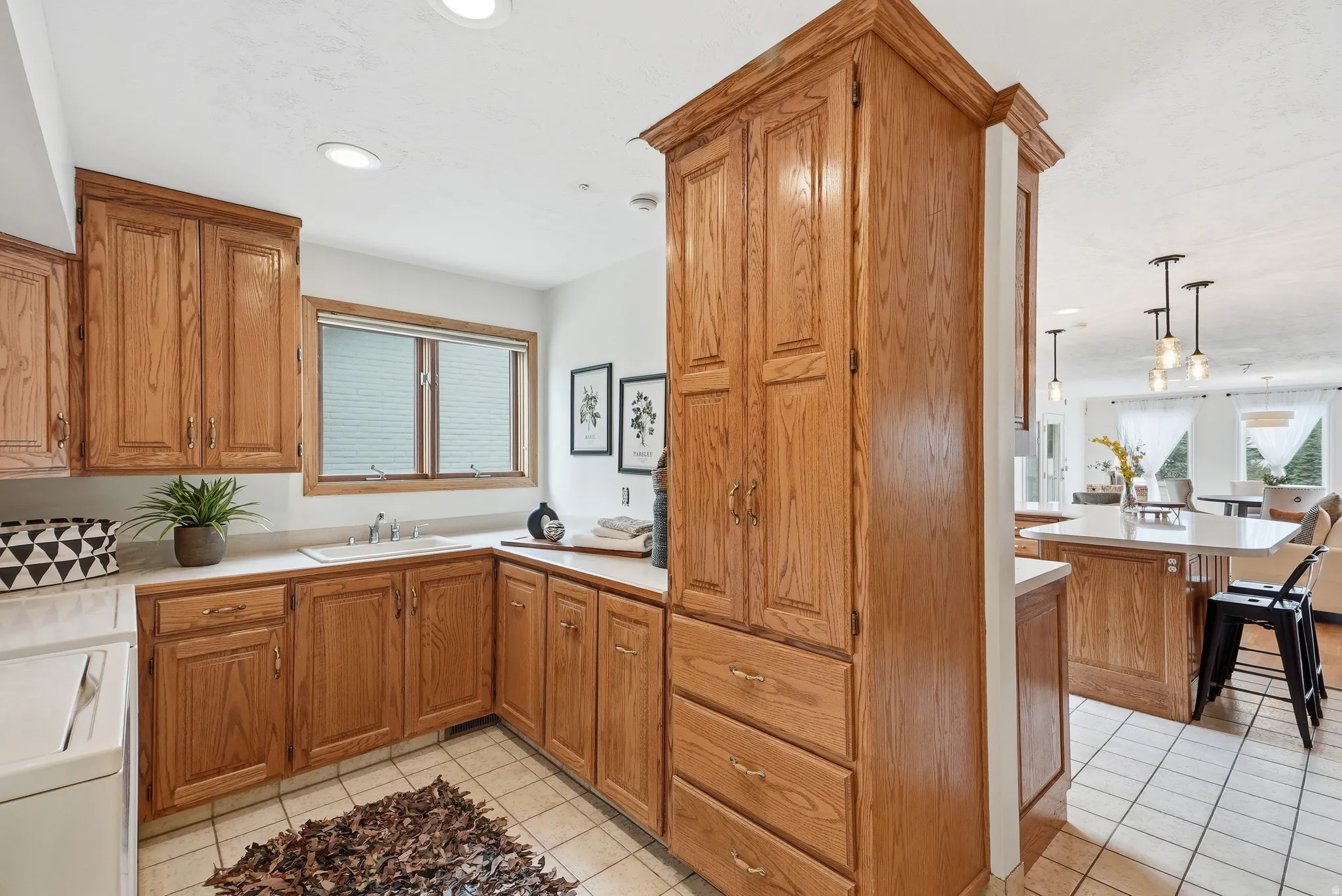 Wood-finish cabinetry with abundant storage, white countertops, built-in sink with faucet, recessed lighting, and tiled flooring