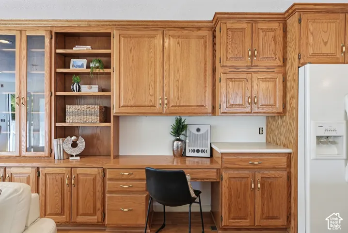 Built-in wood-finish cabinetry, integrated desk space, upper and lower storage, glass-front display cabinets, and neutral countertops