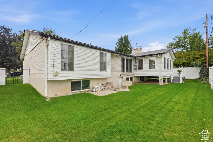 Expansive green lawn, white horizontal siding, brick accent walls, and a multi-level deck with stairs