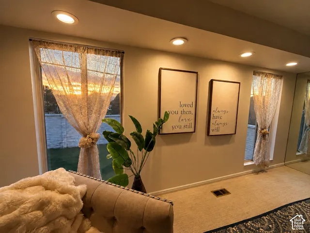 Recessed ceiling lighting, multiple large windows, wall-to-wall carpeting, and a full-height mirrored wall