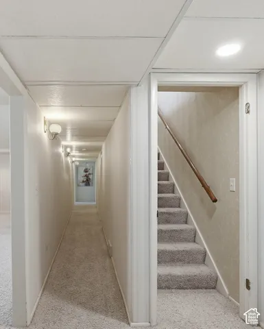Carpeted flooring throughout, recessed ceiling lighting, wall-mounted light fixtures, and a wooden handrail